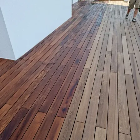 Eine Nahaufnahme einer Holzterrasse mit einer Person, die darauf läuft. Die Terrasse hat eine Mischung aus braunen und hellbraunen Holzdielen.