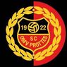 Ein Logo eines Sportvereins mit einem Schilddesign, das die Nummer 19 links, 22 rechts und SC Protties in der Mitte zeigt, umgeben von einem gelben Lorbeerkranz auf rotem Hintergrund.