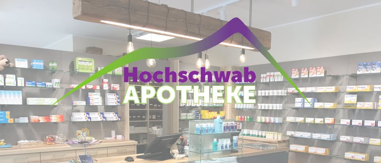 Das Innere einer Apotheke mit einem hölzernen Tresen, Regalen mit verschiedenen Produkten und einem Monitor auf dem Schreibtisch. Der Name der Apotheke 'Hochschwab APOTHEKE' ist prominent angezeigt.