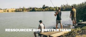 Zwei Männer fischen auf einer Veranda mit einem See im Hintergrund. Ein Mann sitzt, der andere steht. Beide halten Angelruten.