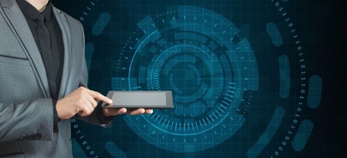 Ein Geschäftsmann in einem Anzug hält ein Tablet mit einer komplexen digitalen Benutzeroberfläche im Hintergrund. Die Benutzeroberfläche ist blau und weiß mit einem kreisförmigen Muster.
