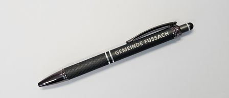 Ein schwarzer Stift mit silberner Spitze und schwarzem Griff wird auf einer weißen Oberfläche präsentiert. Der Körper des Stifts hat den Text 'GEMEINDE FUSSAC' in weiß aufgedruckt.