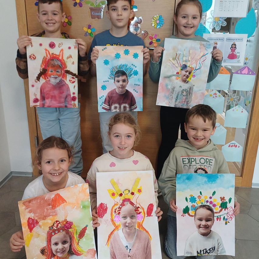 A group of children with painted portraits of themselves, smiling and posing for a photo. The paintings have vibrant colors and whimsical designs.