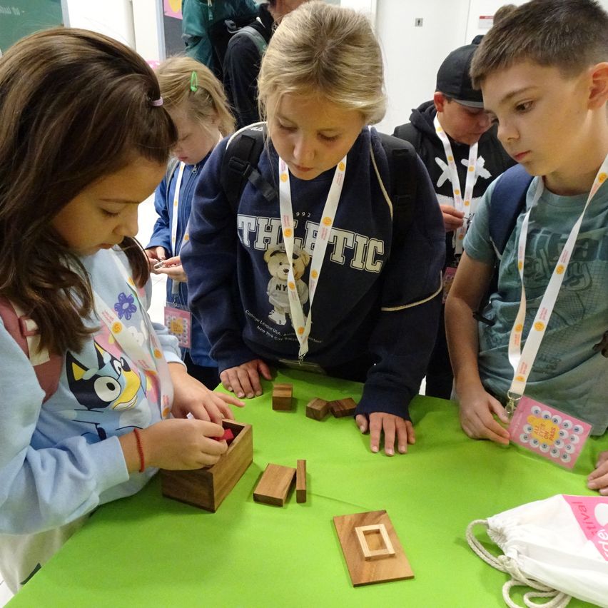 Eine Gruppe von Kindern spielt mit Holzklötzen auf einem grünen Tisch.