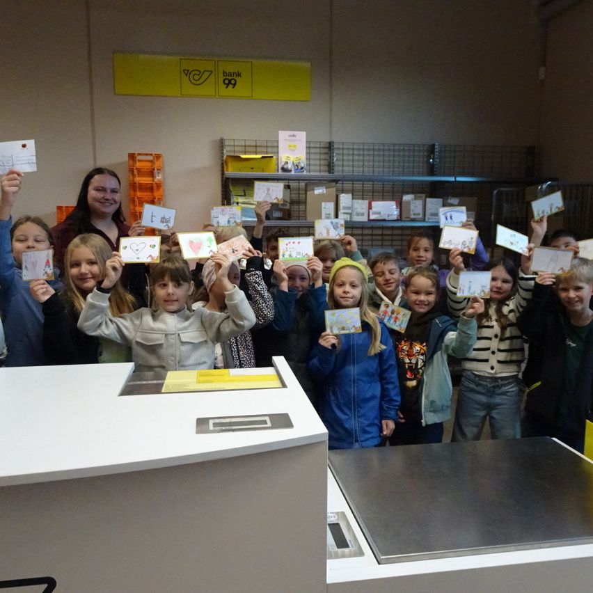 Eine Gruppe von Kindern und zwei Erwachsenen steht in einem Raum und hält Karten hoch.
