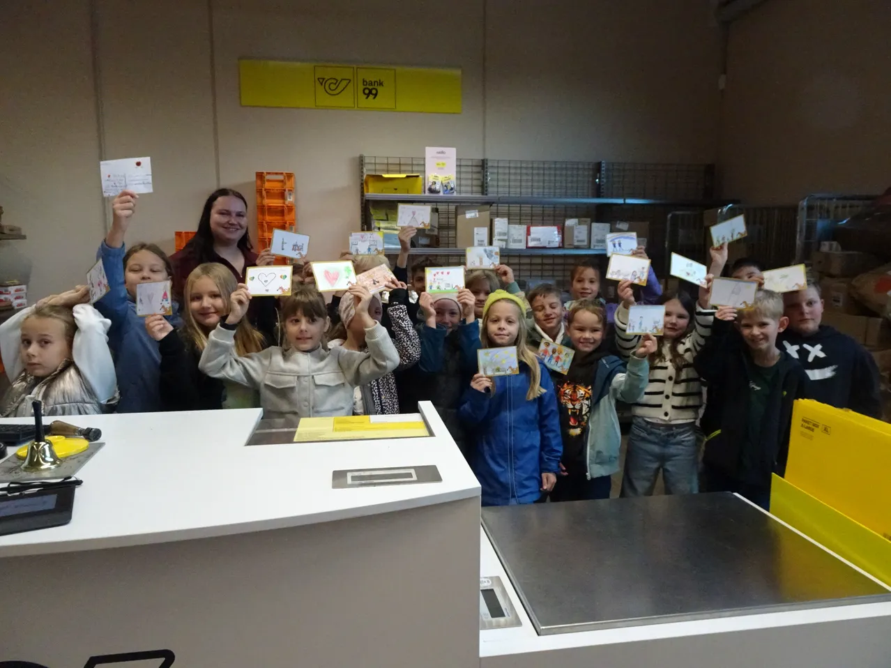 Eine Gruppe von Kindern und zwei Erwachsenen steht in einem Raum und hält Karten hoch.