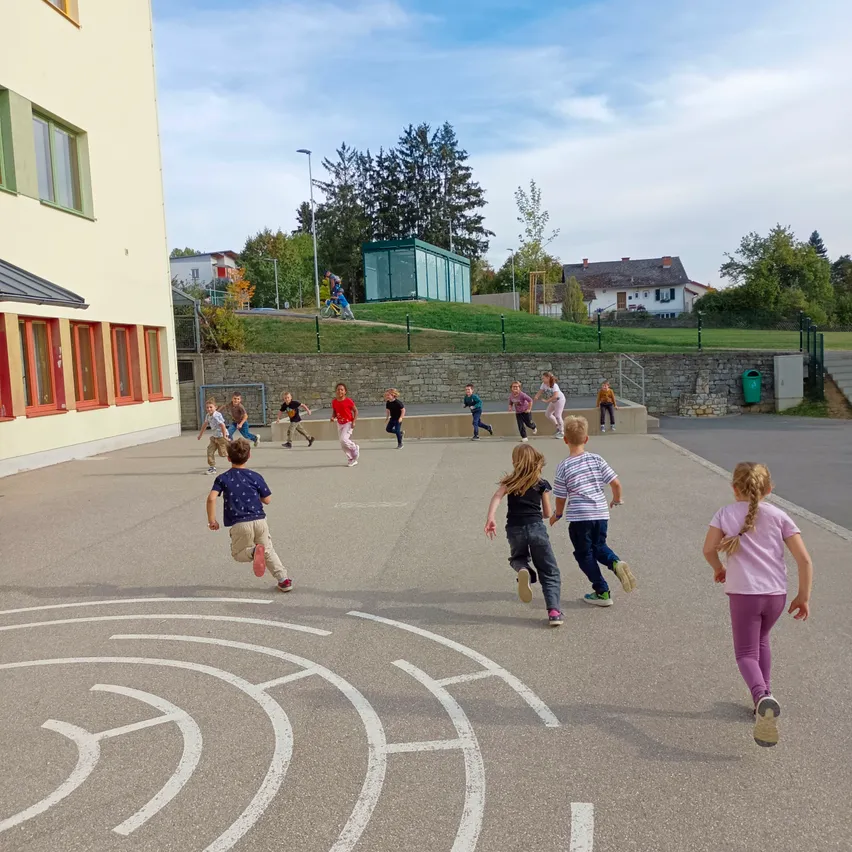 Eine Gruppe von Kindern läuft auf einem Spielplatz um einen kreisförmigen Pfad.