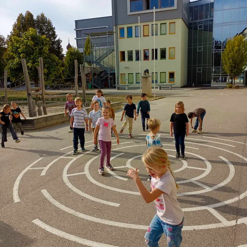 Eine Gruppe von Kindern spielt in einem Labyrinth auf einem Spielplatz.