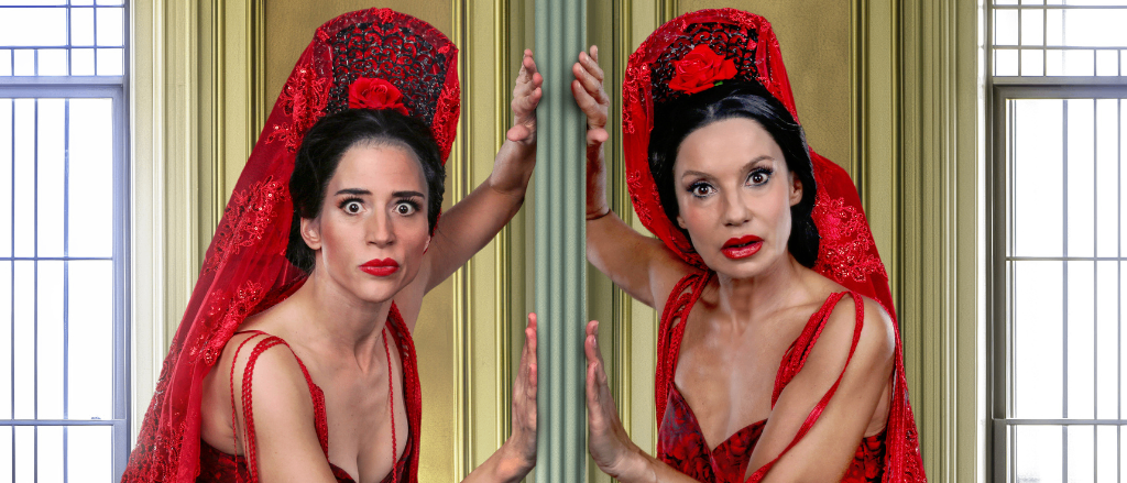 Zwei Frauen in roten Kleidern mit Spitzenschleiern und roten Rosen auf den Köpfen posieren hinter einer goldenen Tür.