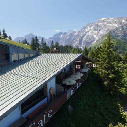 Eine Luftaufnahme eines Cafes mit Metalldach und verschneiten Bergen im Hintergrund.