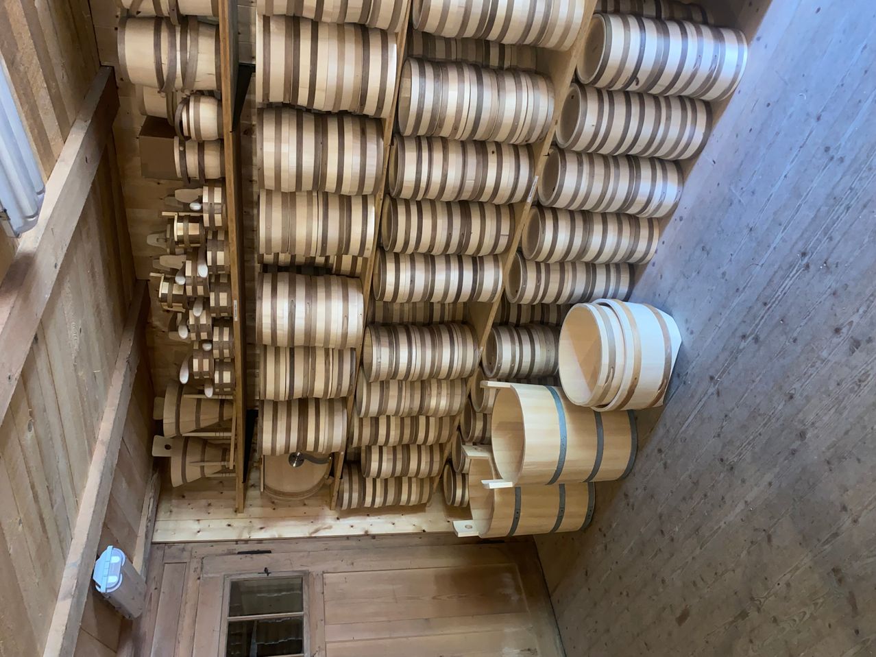A wooden room filled with neatly stacked barrels. Each barrel is made of wood with stripes. A few are placed on the floor.