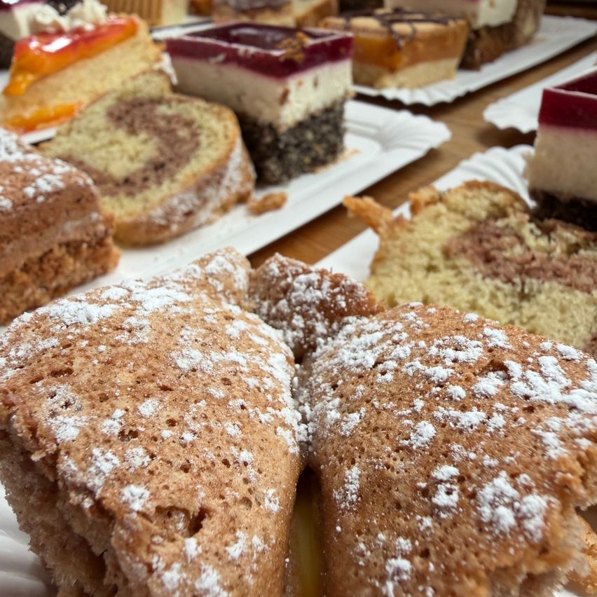 A close-up view of various desserts on plates, including a slice of cake with powdered sugar on top.