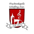 Das Logo zeigt einen roten Schild mit einem Violinschlüssel und einem Kirchturm. Der Text lautet 'Trachtenkapelle Schiefläng/Lav. seit 1879'.