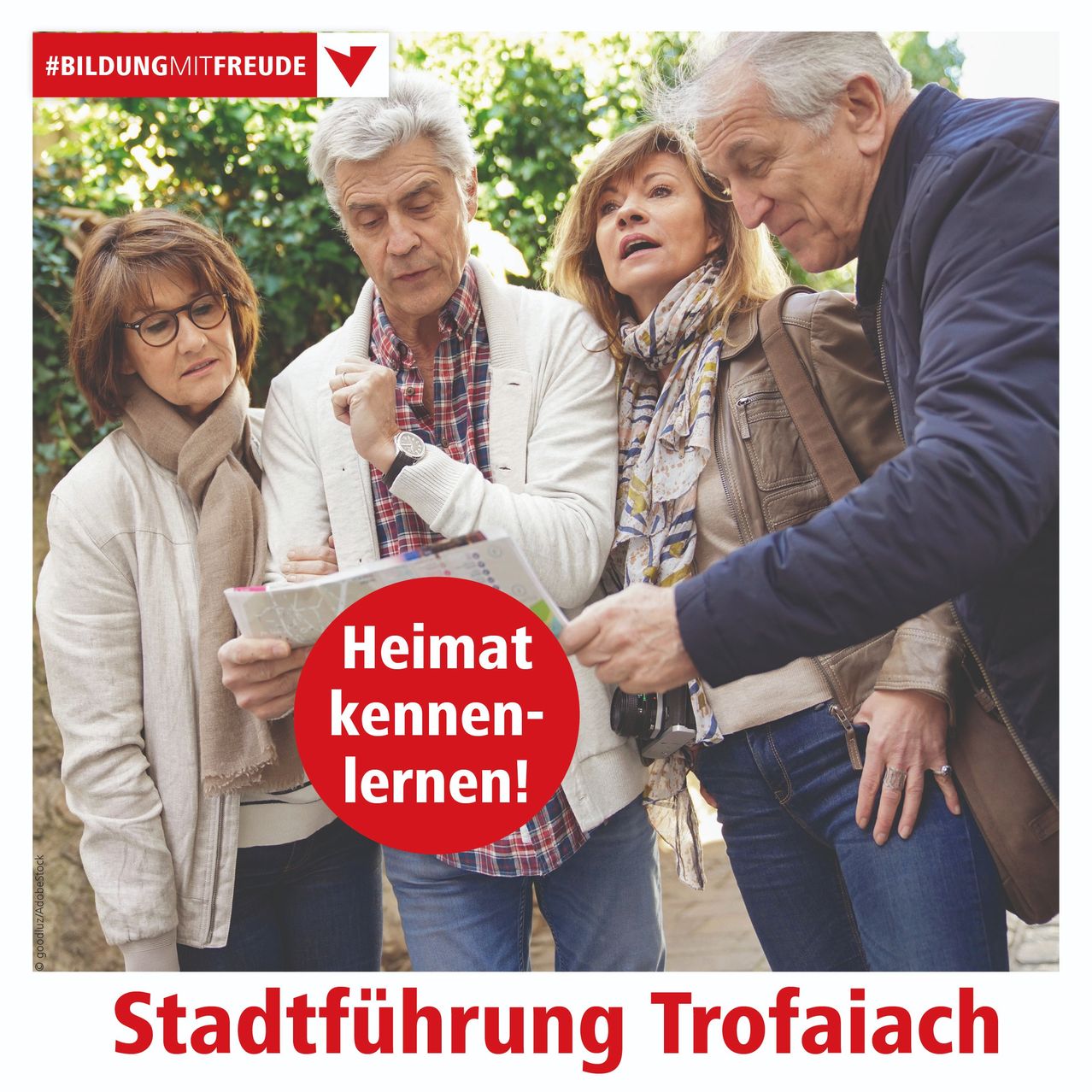 Vier ältere Erwachsene sind bei einer Stadtführung in Trofaiach, schauen sich eine Karte an und diskutieren etwas. Der Mann auf der rechten Seite trägt eine blaue Jacke. Ein roter Kreis mit dem Text 'Heimat kennen-lernen!' erscheint auf der Karte.