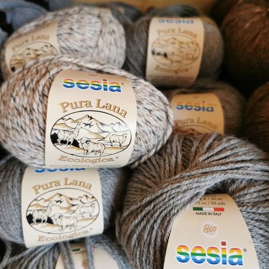 Stapel von Wolle, beschriftet mit 'Sesia Pura Lana Ecologica', mit Illustrationen von Schafen und Bergen, hergestellt in Italien.