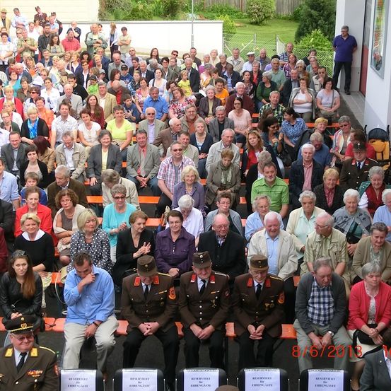 Gruppe älterer Menschen, die in Reihen sitzen, einige in Militäruniformen, mit einem Mann in der Mitte, der sein Kinn hält, am 6. August 2013.