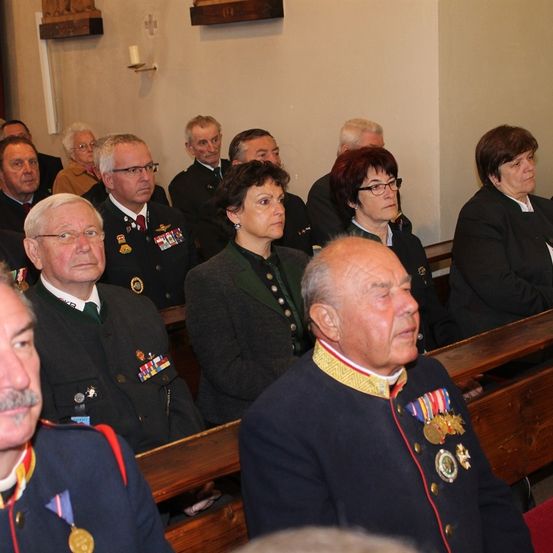 Eine Gruppe von Menschen sitzt in einer Kirche. Sie sind in Uniformen gekleidet und scheinen einem Gottesdienst zuzuhören.