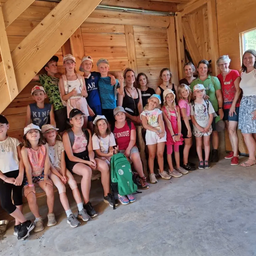 Eine Gruppe von Kindern und Erwachsenen posiert in einem Holzraum für ein Foto.