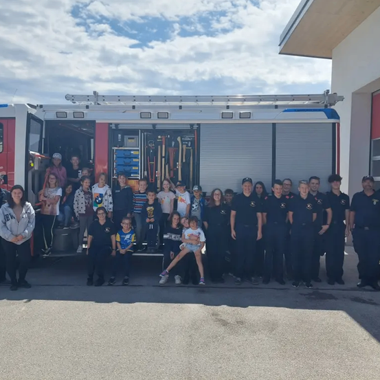 Eine Gruppe von Kindern und Erwachsenen posiert für ein Foto vor einem Feuerwehrwagen.