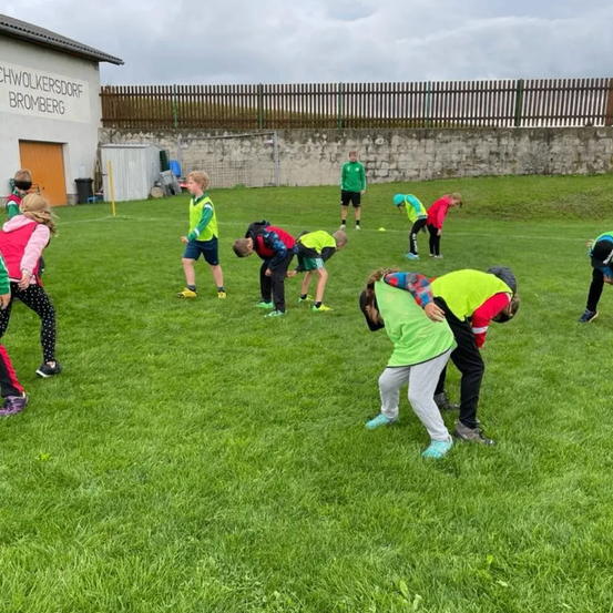 Eine Gruppe von Kindern spielt auf einem Rasenfeld vor einem Gebäude mit dem Namen "Schwolkersdorff Bromberg".