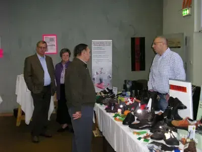 Vier Menschen stehen um einen Tisch voller Schuhe und unterhalten sich miteinander.