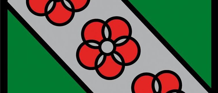 Ein Schild mit einem grünen unteren Teil und einem grauen oberen Teil, versehen mit drei roten Blumen, die in einer Reihe auf dem grauen Teil angeordnet sind.