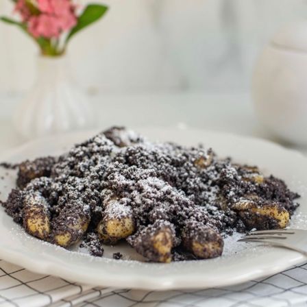 Teller mit knusprigen Kartoffelbällchen, überzogen mit Kakaopulver und Puderzucker.