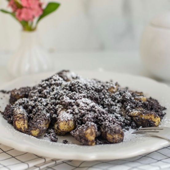 Teller mit knusprigen Kartoffelbällchen, überzogen mit Kakaopulver und Puderzucker.