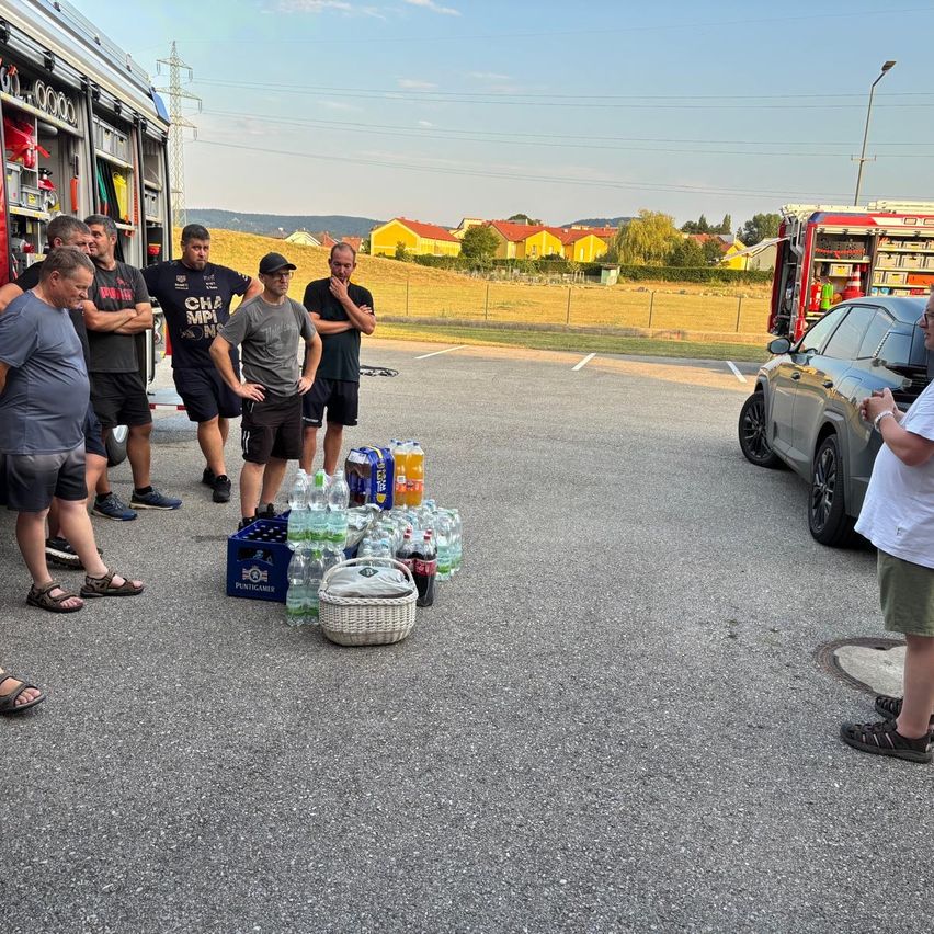 Feuerwehrleute stehen neben einem Getränkeberg in Österreich