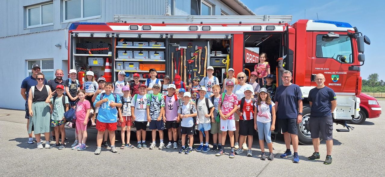 Kinder und Erwachsene vor einem Feuerwehrauto der Freiwilligen Feuerwehr Breitenau