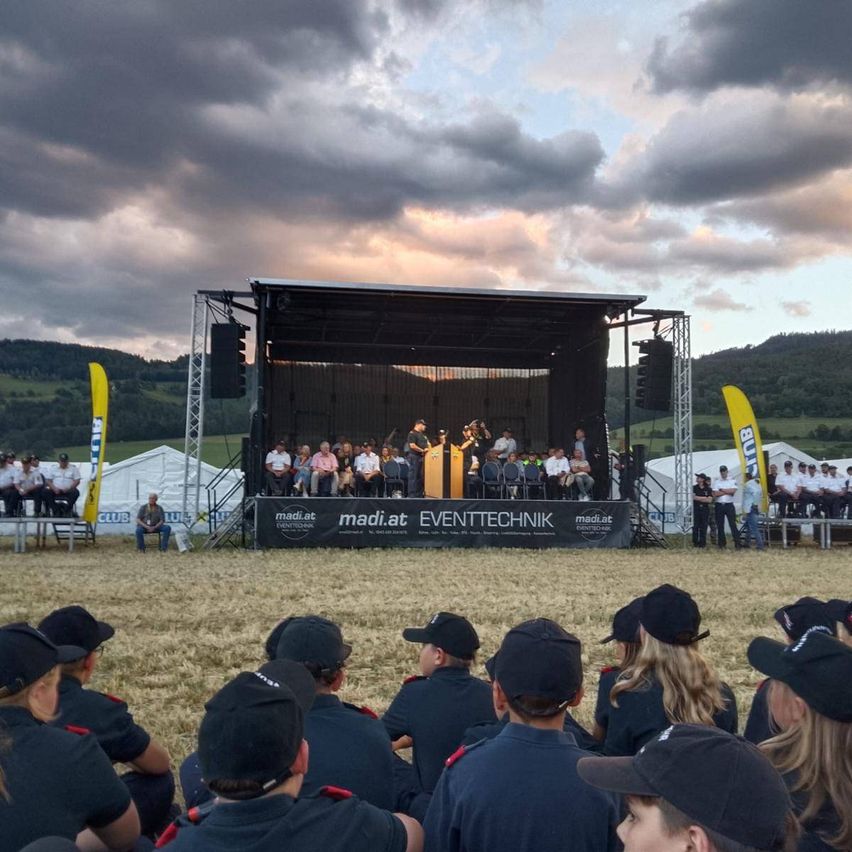 Feuerwehrfest mit Bühne und Gästen im Freien bei Dämmerung