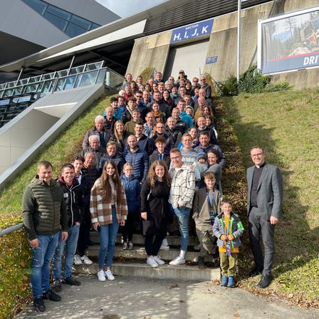 Eine Gruppe von Menschen posiert auf den Stufen eines Stadions für ein Foto. Sie sind alle in Winterkleidung gekleidet.