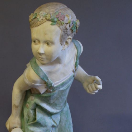 Eine Porzellanstatue eines jungen Mädchens mit Blumen im Haar, das ein grünes Kleid trägt und nach rechts schaut.