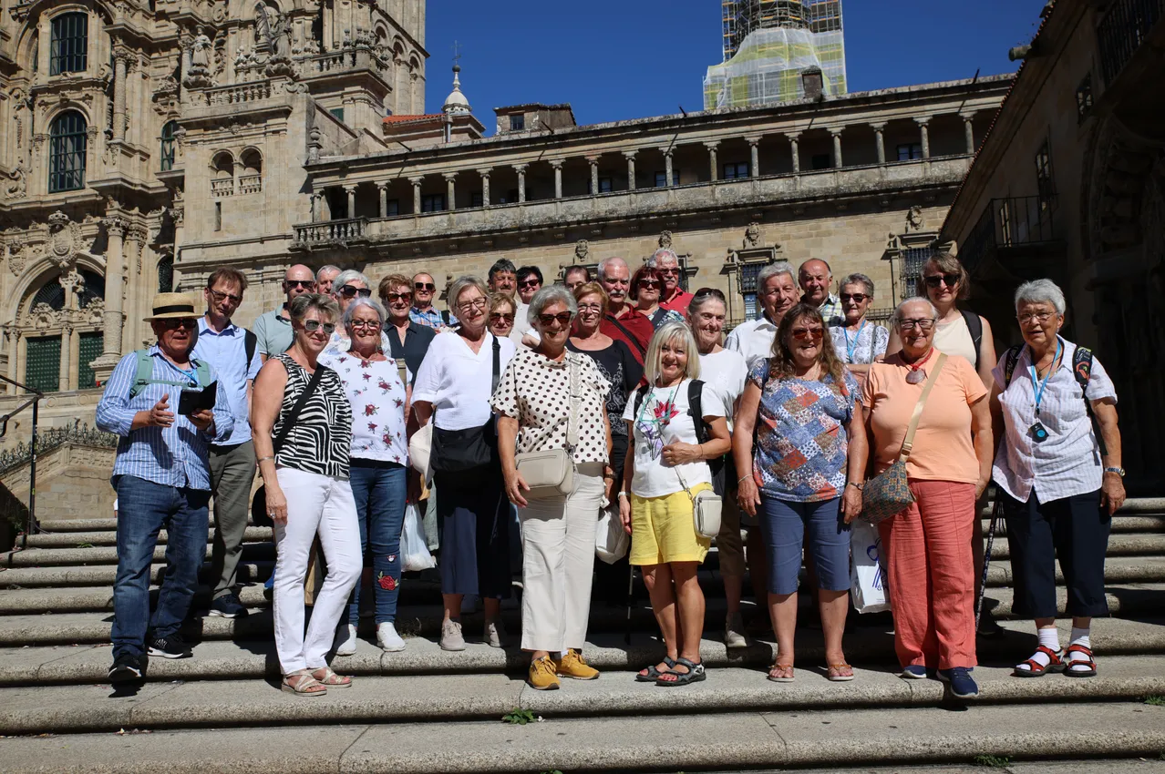 Eine Gruppe von Menschen, wahrscheinlich Touristen, steht auf den Stufen eines historischen Gebäudes und lächelt für ein Foto.