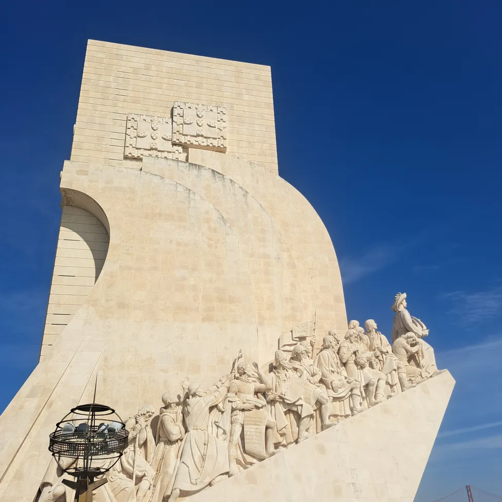 Ein großes Steinmonument mit einer Reihe von Figuren, die in seine Seite gemeißelt sind, unter einem klaren blauen Himmel.