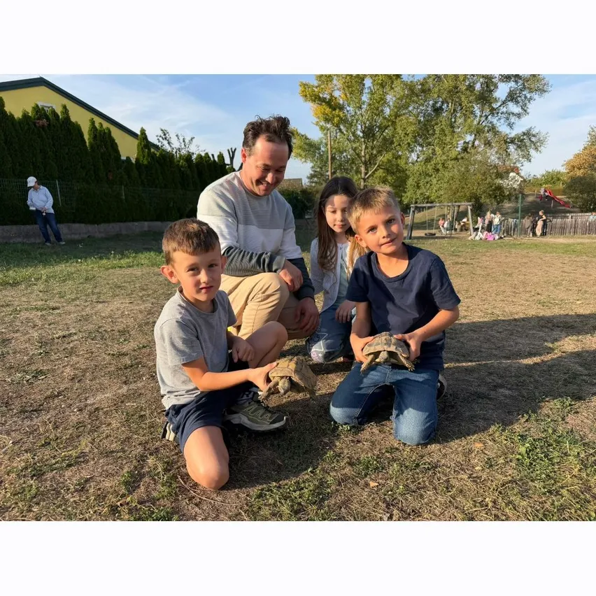 Eine Familie genießt einen Tag im Park. Der Vater kniet mit zwei jungen Jungen und sie halten alle eine Schildkröte.