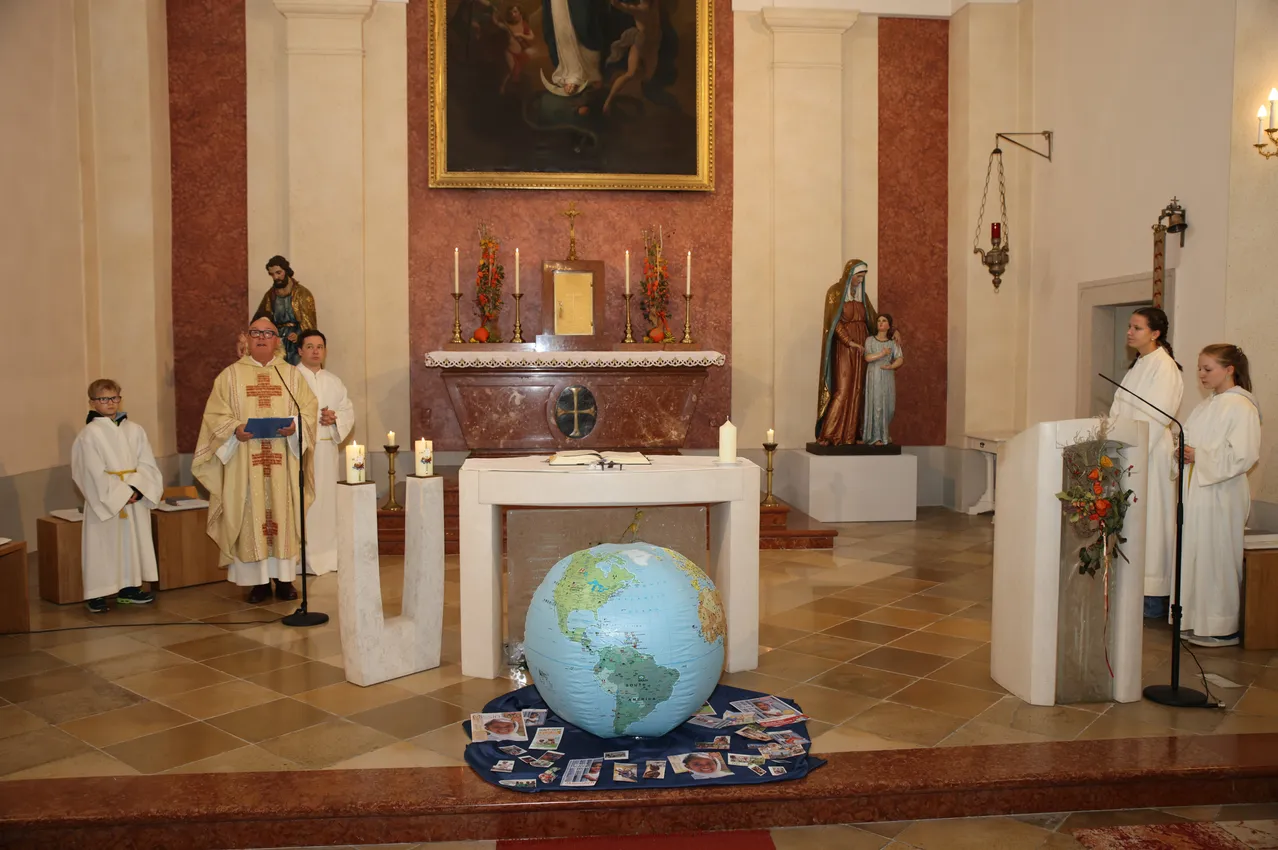 Eine religiöse Zeremonie findet in einer Kirche mit einer Erdekugel in der Mitte statt.