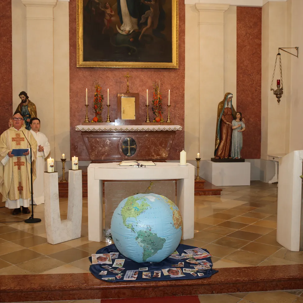 Eine religiöse Zeremonie findet in einer Kirche mit einer Erdekugel in der Mitte statt.