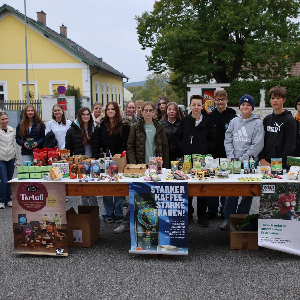 Eine Gruppe von Menschen steht hinter einem Tisch voller verschiedener Produkte.