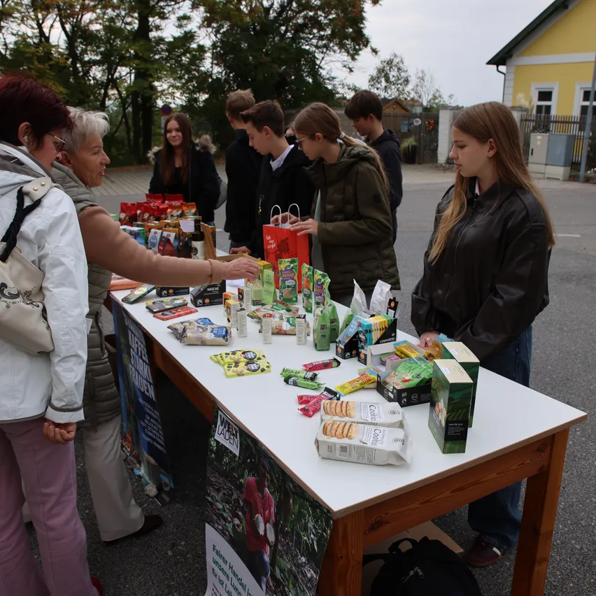 Eine Gruppe von Menschen versammelt sich um einen Tisch mit verschiedenen Gegenständen.