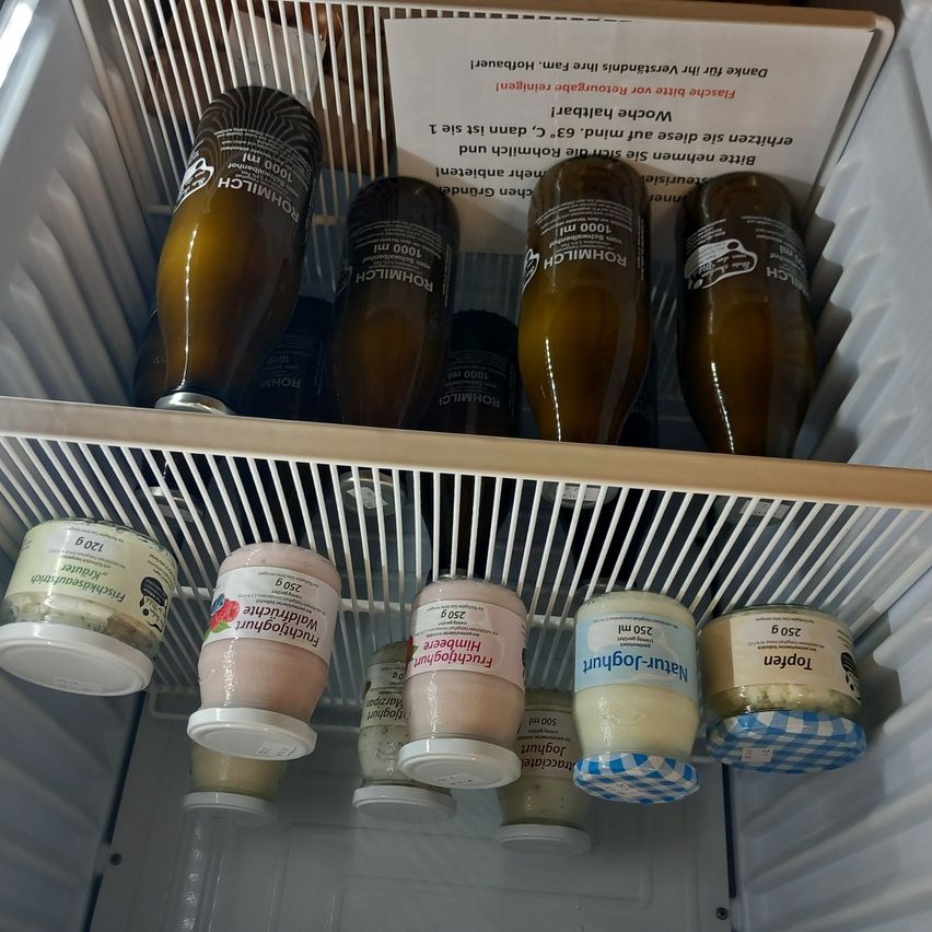 A refrigerator shelf with various containers and bottles, including two large bottles labeled "Knorr" and several smaller containers with white lids. A note in the corner reads, "Keep food safe and clean."