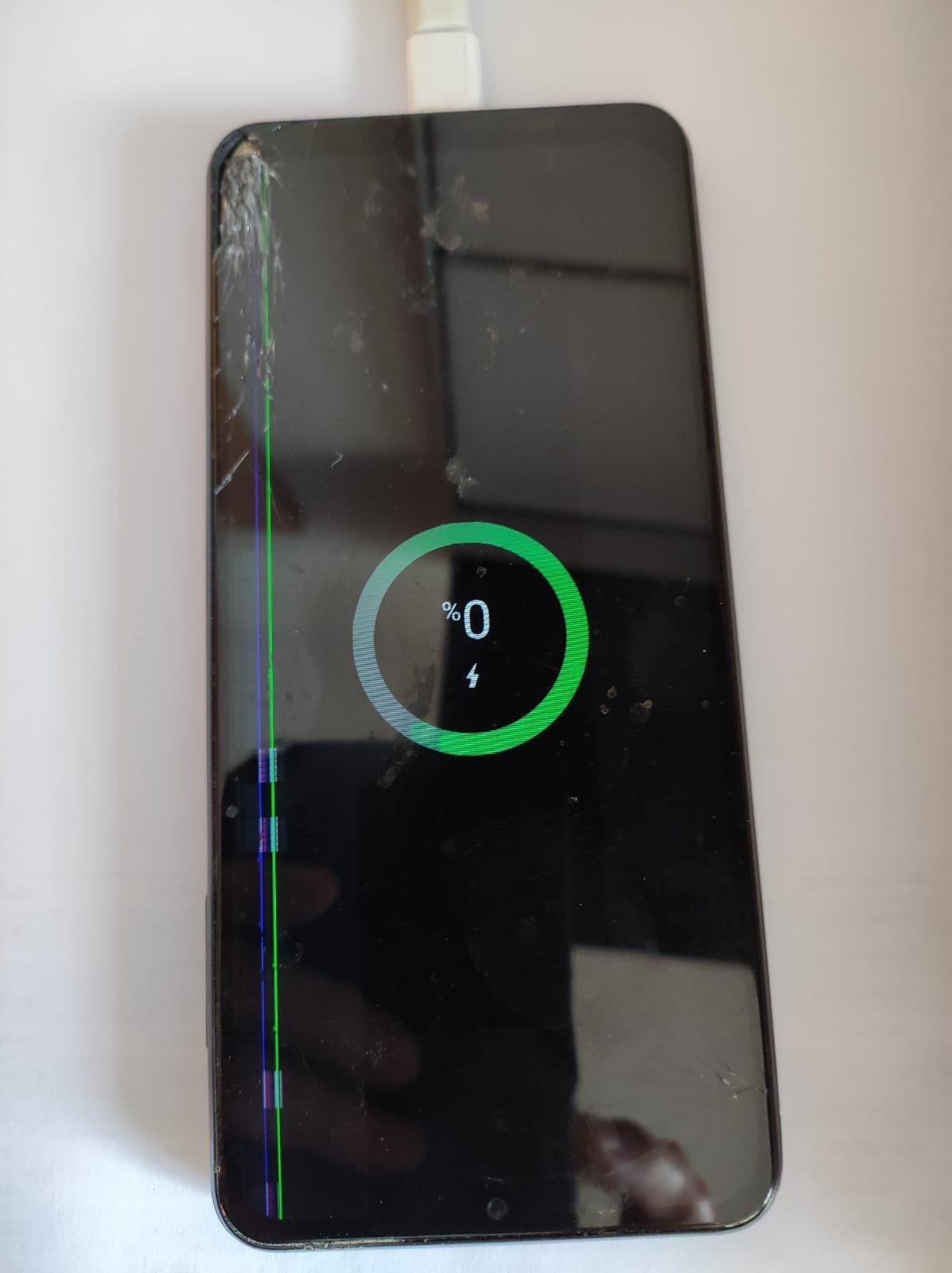 Gesprungenes Smartphone-Display mit Ladesymbol des Akkus bei 0% geladen.