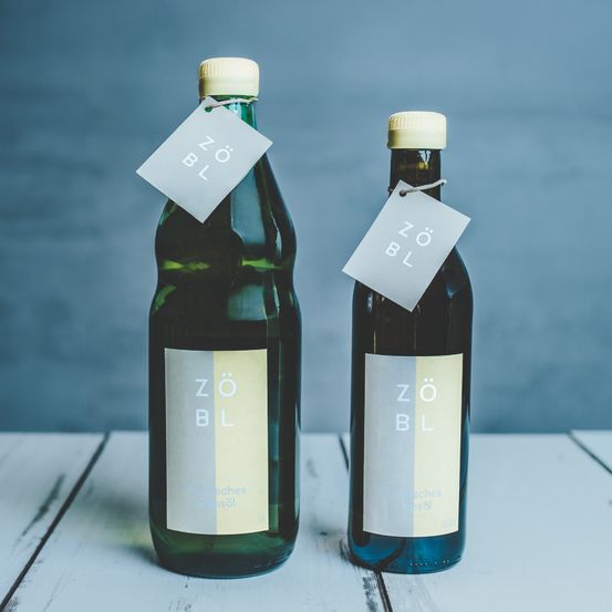 Zwei grüne Flaschen mit dem Aufkleber ZBL auf einem weißen Tisch. Jede Flasche hat einen weißen Aufkleber mit demselben Label.