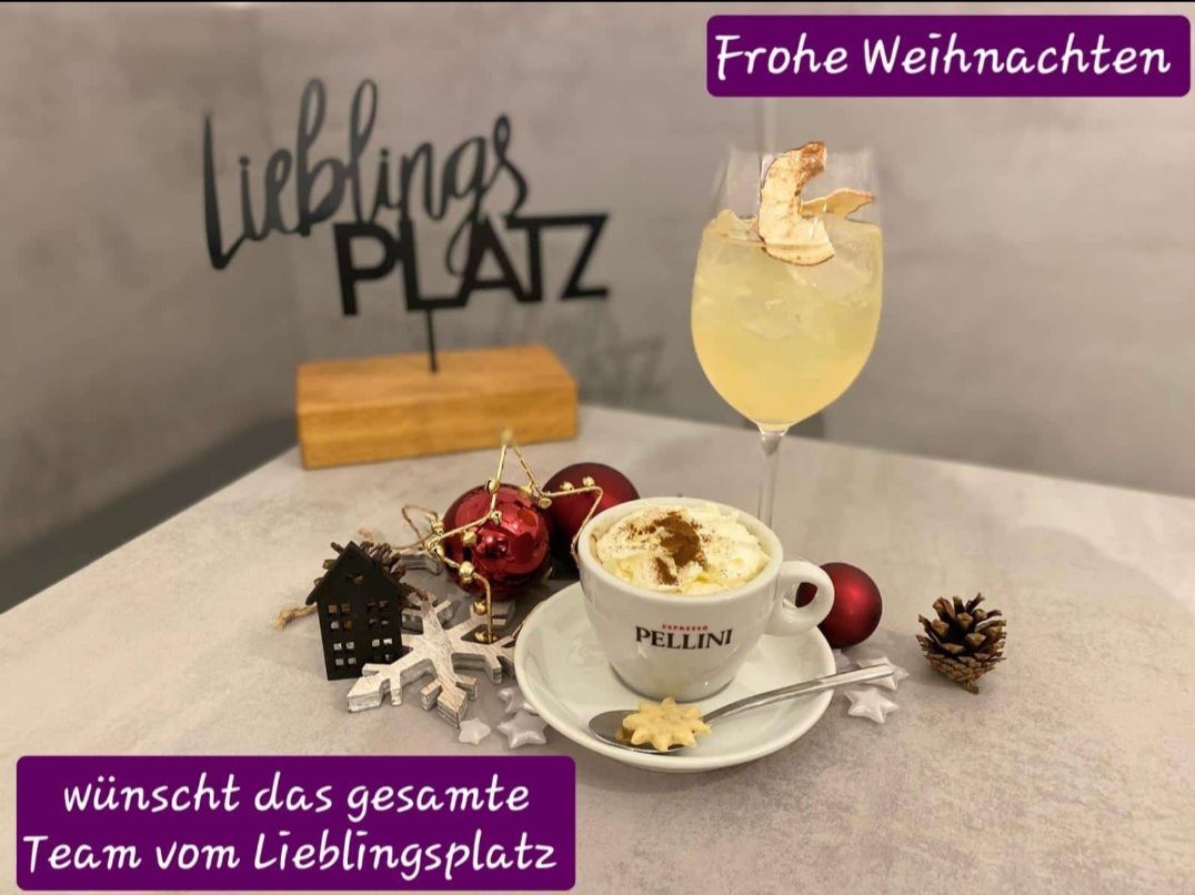 Eine Tasse Kaffee und ein Weinglas auf einem Tisch mit Weihnachtsdekoration und einem Schild, das 'Frohe Weihnach' sagt.