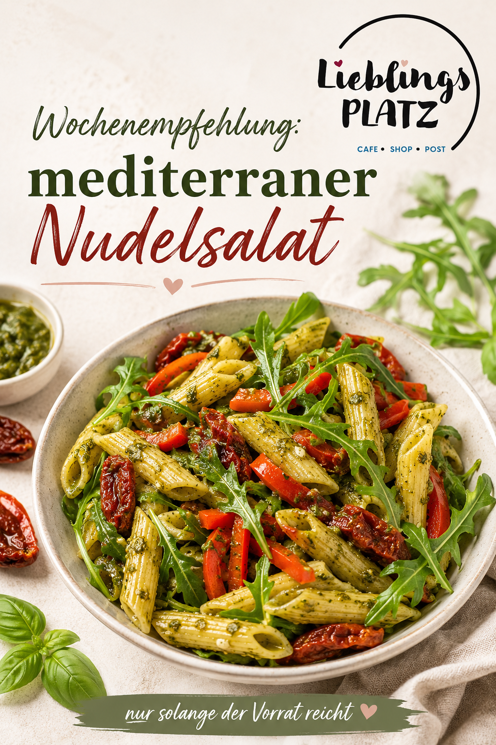 Eine Schüssel mediterraner Nudelsalat mit Tomaten, Pesto und Rucola. Es ist mit Basilikum und getrockneten Tomaten garniert. Das Bild hat einen unscharfen Hintergrund.