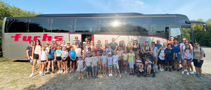 Eine Gruppe von Menschen steht vor einem großen Bus. Sie alle lächeln für ein Foto.