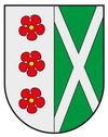 Ein Schild, der in zwei Teile geteilt ist, links drei rote Blumen und rechts ein weißes Kreuz auf grünem Hintergrund.