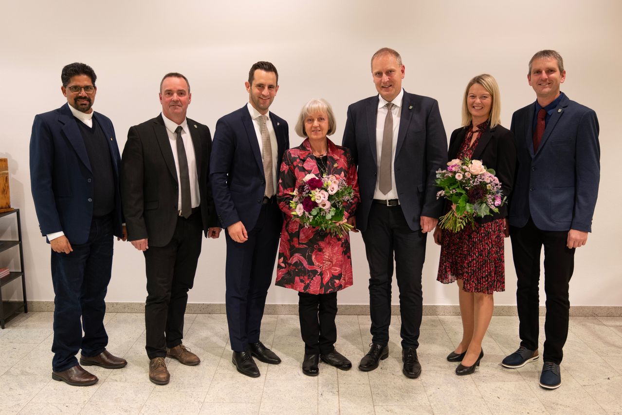 A group of people dressed in formal attire are standing together for a photograph. They are smiling and appear to be celebrating a special occasion.