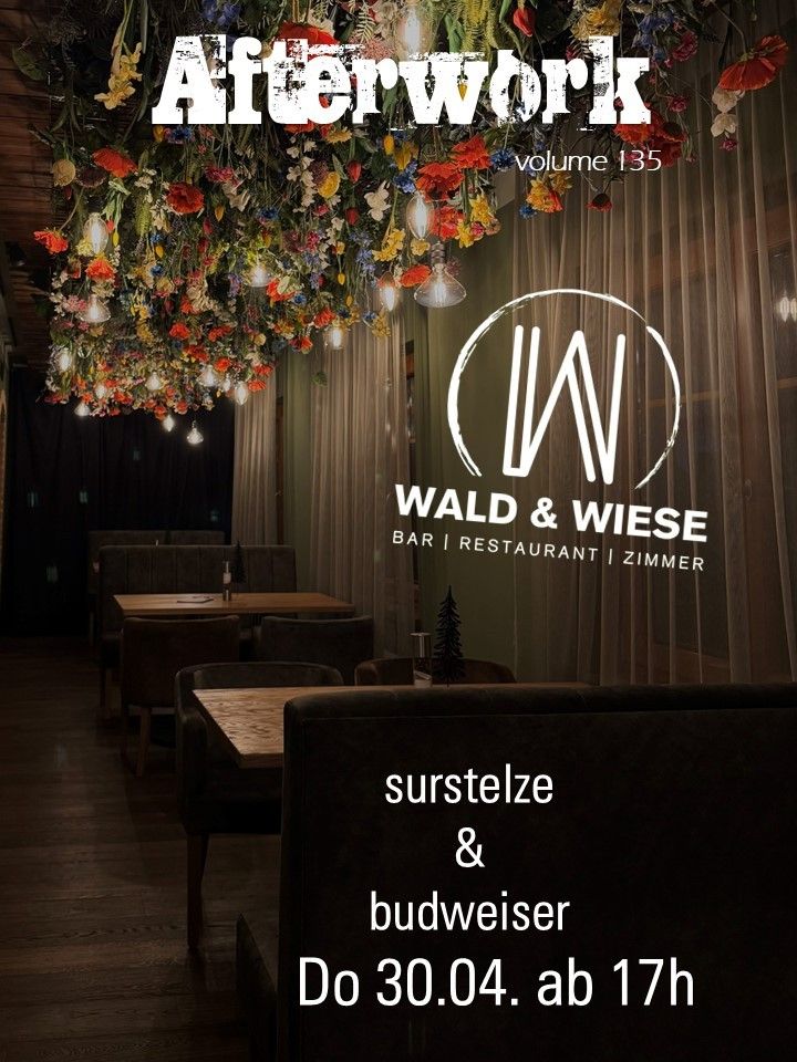 Ein Restaurant mit einer Blumendecke, Holztischen und Stühlen und einem Logo für Wald & Wiese. Ein Baum und eine Flasche stehen auf dem Tisch. Das Bild zeigt Surstelze & Budweiser.