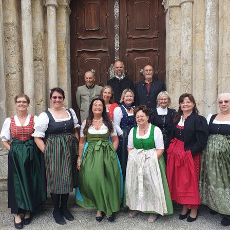 Eine Gruppe von Menschen in traditioneller Kleidung posiert für ein Foto vor einer großen Holztür.
